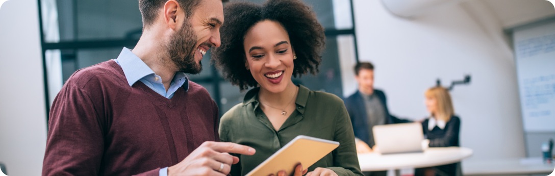 Man and woman standing while looking at tablet